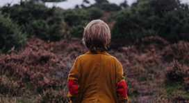 Niño con chaqueta de pana y coderas en el bosque